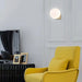 Solja – Nordic glass orb wall sconce in modern living room – gold single head above accent chair