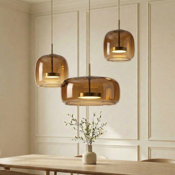 Three pendant lights with amber glass shades hanging above a wooden table.