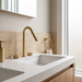 Kilde brushed gold bathroom vanity faucet on a travertine backsplash – Japandi styling