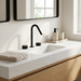 Kilde black widespread bathroom faucet on a white oak vanity with travertine accessories
